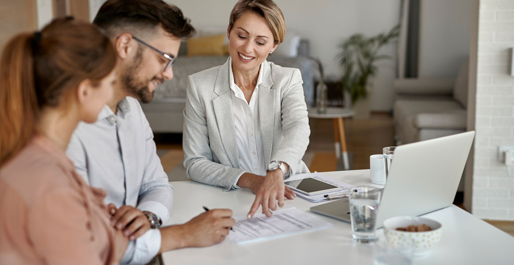 Couple consultant des documents d'épargne retraite dans un salon contemporain avec brochures PER et assurance vie